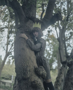 Portrait of smiling young woman against tree trunk