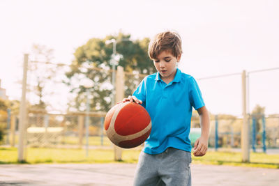 Boy playing with basketball in court