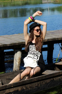 Young woman in sunglasses looking away while standing in boat by lake