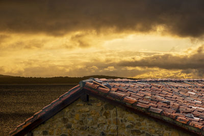 Tilt image of roof and building against sky during sunset