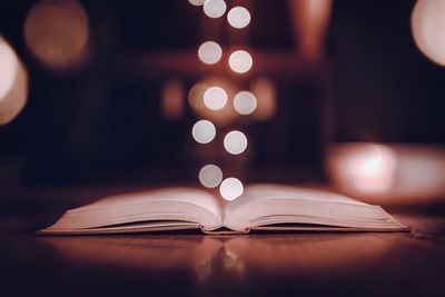 Close-up of illuminated defocused lights over books on table