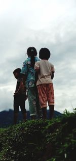 Rear view of people standing on land against sky