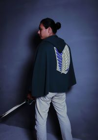 Rear view of man looking away while standing against wall