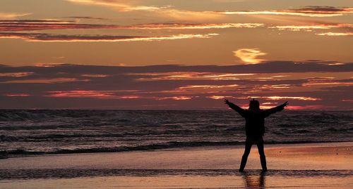 Silhouette of man standing on beach at sunset