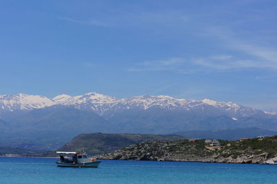 Sailboat on sea by snowcapped mountains against sky