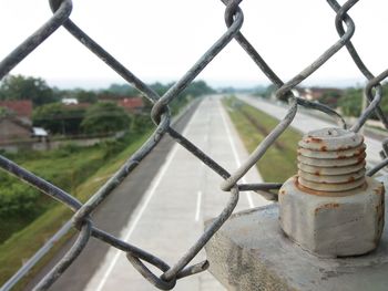 Close-up of rusty fence on field against sky