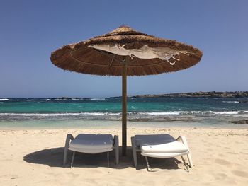 Deck chairs on beach against clear sky