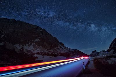 Light trails on road against sky at night