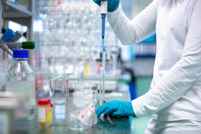 Midsection of scientist holding vial in laboratory