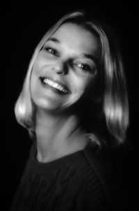Portrait of young woman against black background