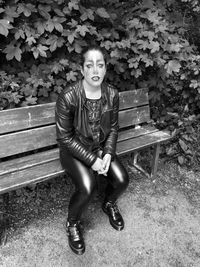 Portrait of young woman sitting on bench in park