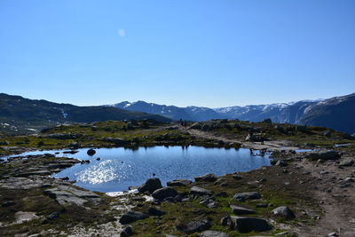 Scenic view of lake and mountains against clear blue sky