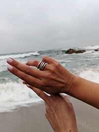 Midsection of person on beach against sky