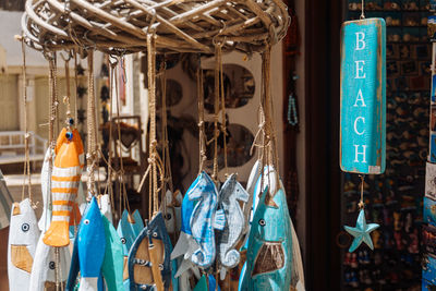 Close-up of wooden ornaments and handmade souvenirs hanging in store for sale at beach.