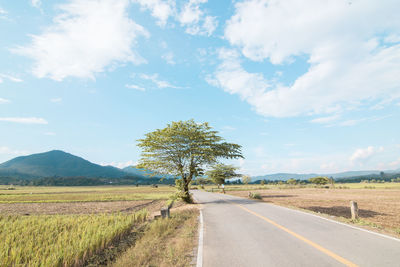 Road amidst field against sky