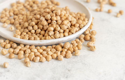 Plate of raw dry chickpea on white table close up