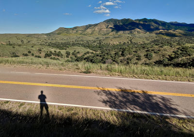 Scenic view of road by mountain against sky
