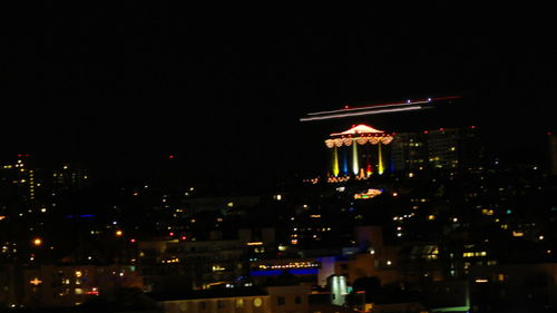 Illuminated city against sky at night