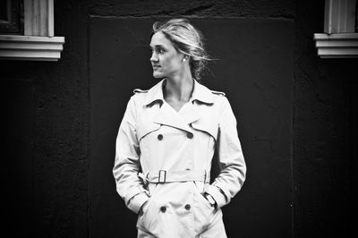 Portrait of young woman standing against building