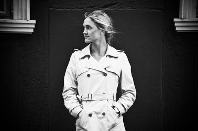 Young woman standing by wall