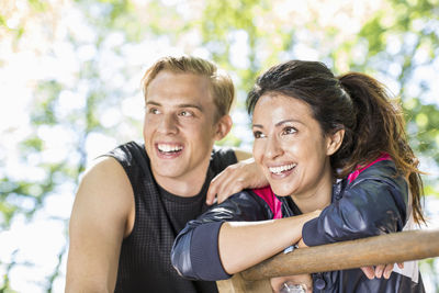 Happy multi-ethnic couple looking away at outdoor gym