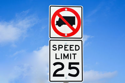 Close-up of road sign against blue sky