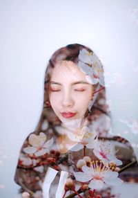 Young woman with flowers against gray background