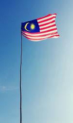 Low angle view of malaysian flag against clear blue sky