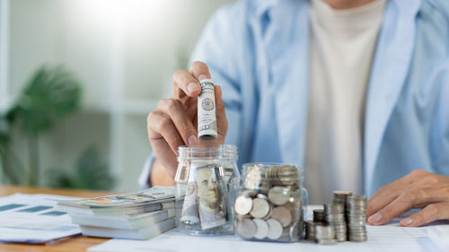 Saving concept the male young adult rolling his cash and putting it into the bottle.