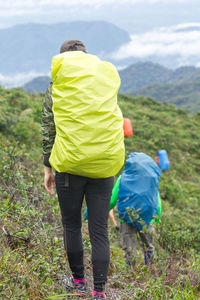 Rear view of people with backpack hiking on mountain against sky