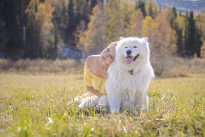 Woman with dog sitting on field during sunny day