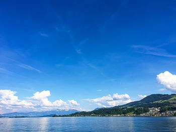 Scenic view of sea and mountains against blue sky