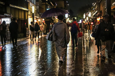 Group of people walking on wet street at night