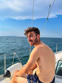 Portrait of shirtless man swimming in sea against sky