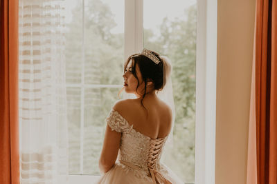 Young woman standing against curtain at home