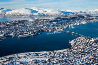 High angle view of city by snowcapped mountain against sky