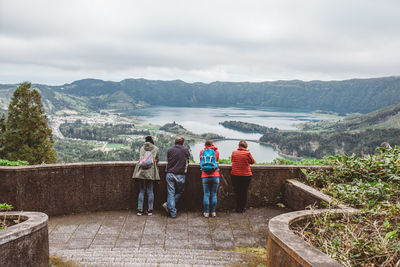 Rear view of people standing on mountain against sky