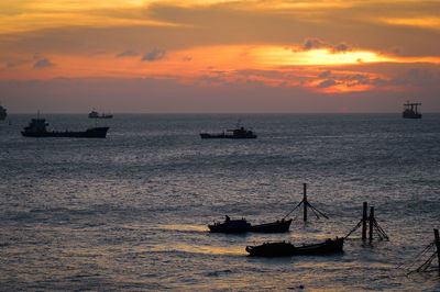 Silhouette boats sailing on sea against cloudy sky during sunset