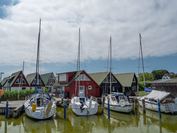 Sailboats moored at harbor against sky