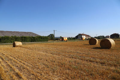 Hay bales on field against clear sky