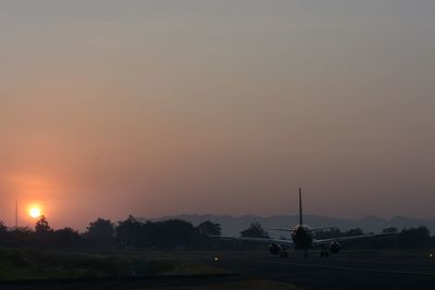 Silhouette airport runway against sky during sunset