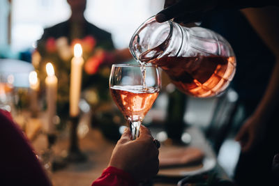 Cropped hand of man pouring drink to friend at dinner party