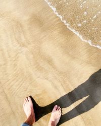 Low section of person standing on sand