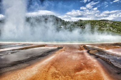 Scenic view of geyser and mountain against sky