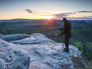 Tall photographer prepare camera for take picture of fall mountains. photograph at colorful valley