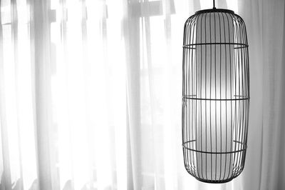 Close-up of pendant light hanging against curtain at home