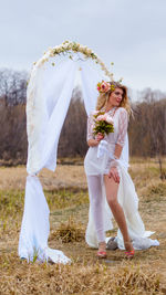 Rear view of woman holding umbrella while standing on field
