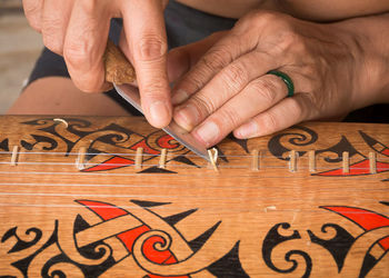 Midsection of man repairing string instrument 