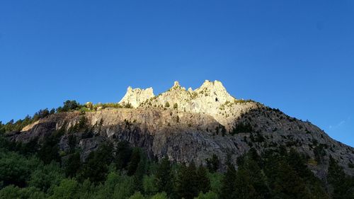 Low angle view of rocks against clear blue sky