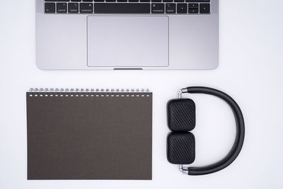 Directly above of spiral notebook with laptop and headphones on gray background